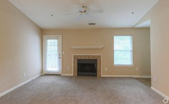 an empty living room with a fireplace and a ceiling fan